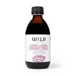 A bottle of elderberry and mânuka Immunity Tonic, featuring a dark amber glass bottle, black cap, and a white label with red and black text, set against a plain white background.